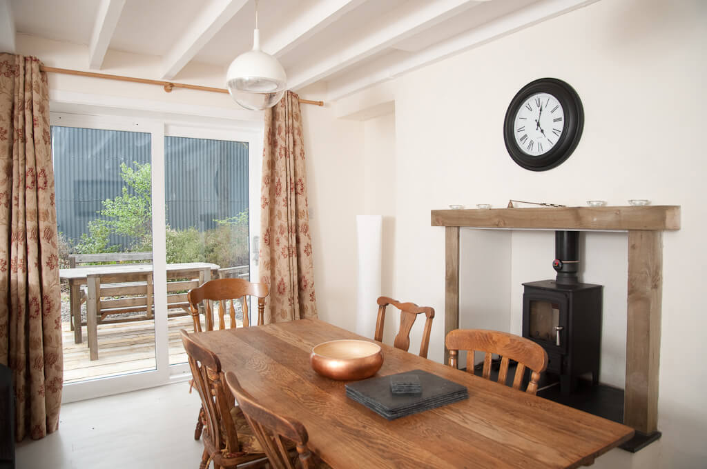 A set of patio doors leads out onto a small deck with a large table.